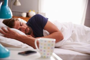 41147087 - sleeping man being woken by mobile phone in bedroom