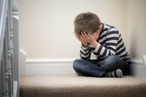 38970956 - upset problem child with head in hands sitting on staircase concept for bullying, depression stress or frustration