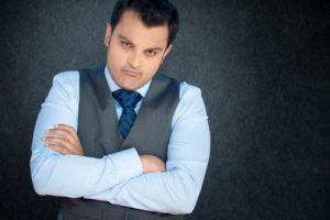 38123108 - closeup portrait, displeased, angry, grumpy business man, bad attitude, arms crossed, folded, looking at you, isolated gray black background. negative human emotion, facial expression, feeling